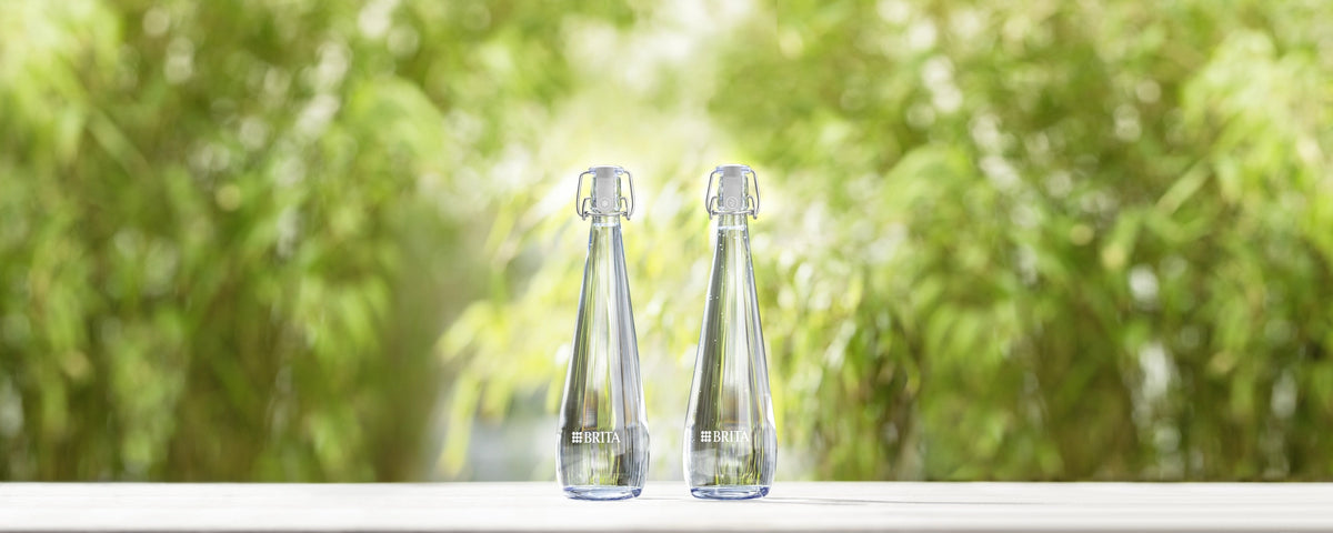 Deux bouteilles Swing posées sur une surface blanche, avec un arrière-plan naturel vert flou