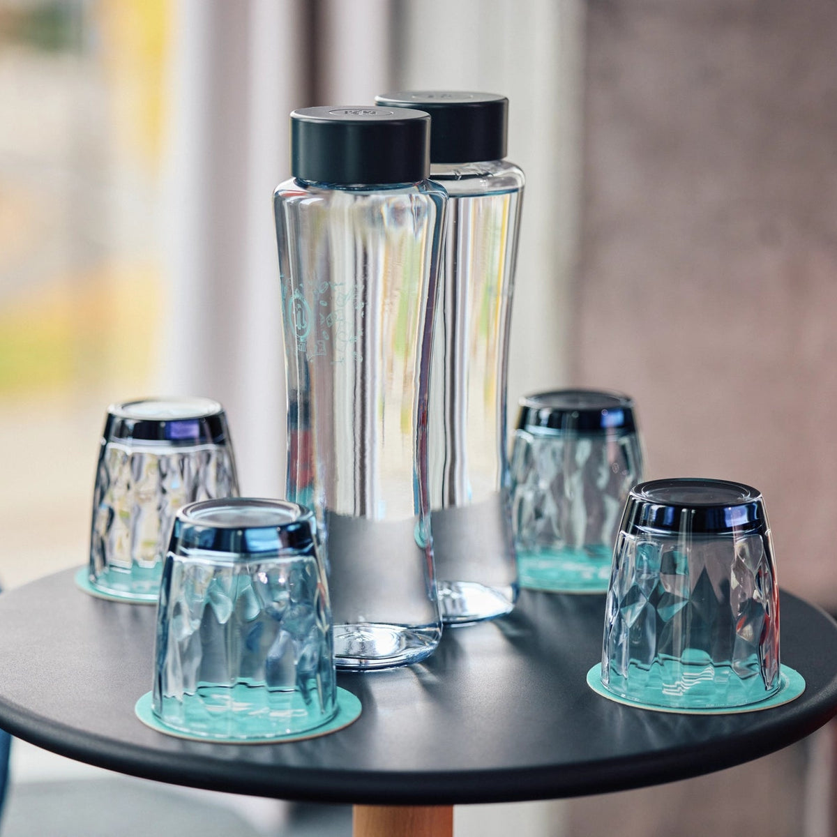 Des bouteilles BRITA Twist avec des bouchons noirs, posées sur une table ronde noire.