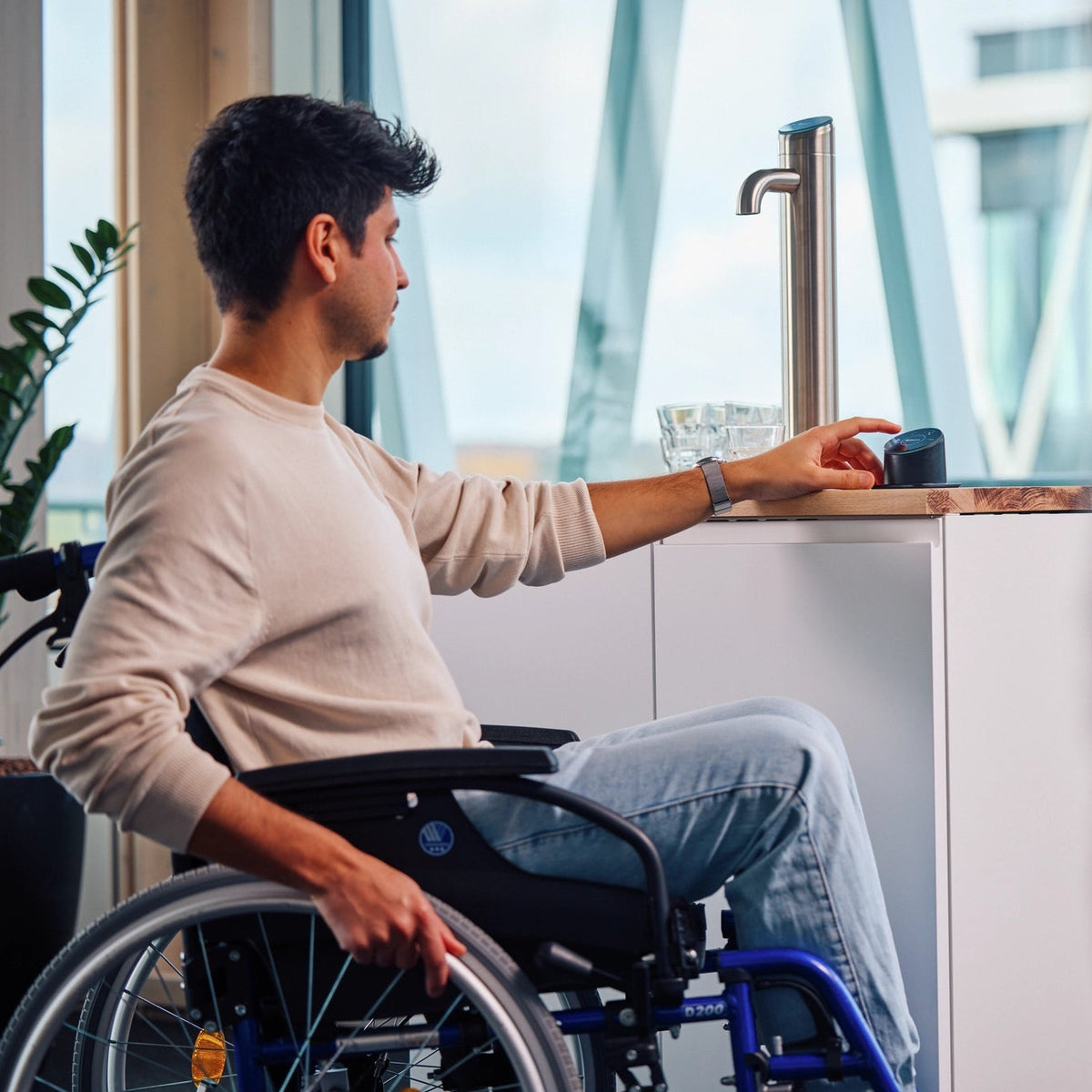 Un homme en fauteuil roulant se sert de l'eau à l'aide d'un panneau « Easy Access » sur un BRITA I-Tap.