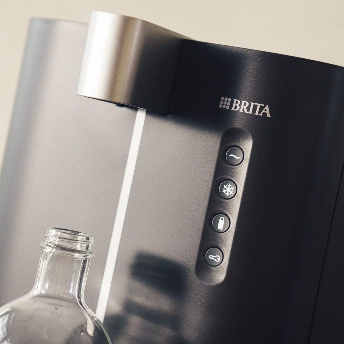BRITA Top Compact avec une bouteille transparente en dessous, sur un fond neutre.