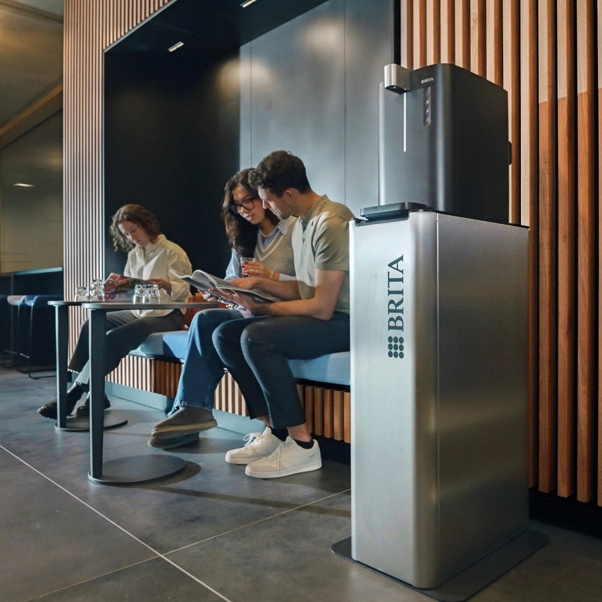 Des personnes assises dans un bureau moderne, à côté d'un fontaines à eau  BRITA Top Compact.
